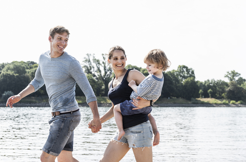 Glückliche Familie bei einem Spaziergang am Flussufer an einem schönen Sommertag, lizenzfreies Stockfoto