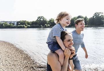 Glückliche Familie bei einem Spaziergang am Flussufer an einem schönen Sommertag - UUF15013