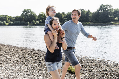 Glückliche Familie bei einem Spaziergang am Flussufer an einem schönen Sommertag - UUF15015