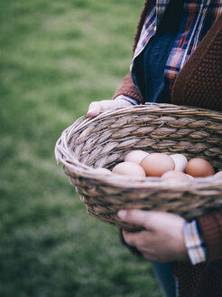 Woman's hands holding basket of fresh brown eggs - RAMAF00055