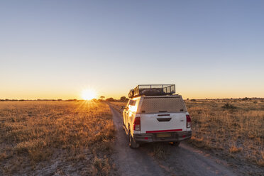 Botswana, Kalahari, Central Kalahari Game Reserve, Geländewagen auf Schotterstraße bei Sonnenaufgang - FOF10230