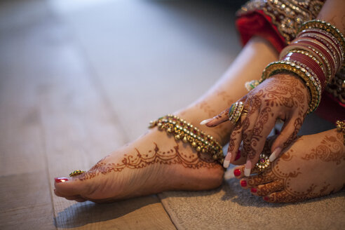 Schmuck wird über den mit Henna bedeckten Händen und Füßen einer indischen Frau getragen. - AURF02430