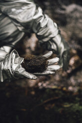 Spaceman exploring nature, holding soil - VPIF00547