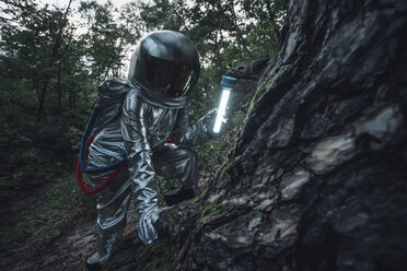 Raumfahrer, der mit einer Taschenlampe die Natur erkundet - VPIF00552