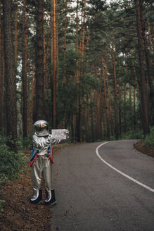 Raumfahrer, der per Anhalter zum Mars fährt, steht auf einer Straße im Wald - VPIF00556