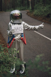 Raumfahrer, der per Anhalter zum Mars fährt, steht auf einer Straße im Wald - VPIF00557