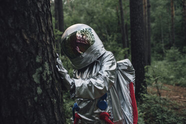 Spaceman exploring nature, examining tree trunk - VPIF00569