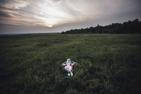 Raumfahrer erkundet die Natur und entspannt sich auf einer Wiese, lizenzfreies Stockfoto
