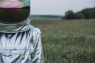 Spaceman exploring nature, meadow reflecting in space hat - VPIF00595