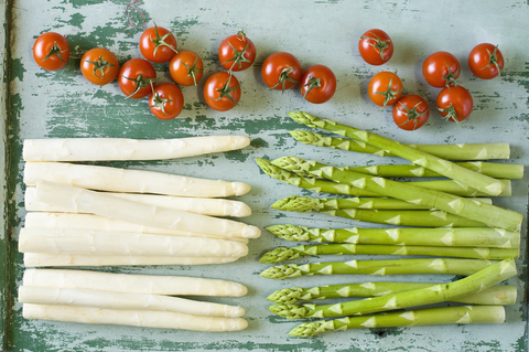 Rohe weiße und grüne Spargelstangen und Tomaten, lizenzfreies Stockfoto