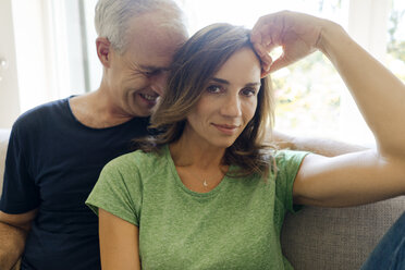 Portrait of happy mature couple sitting on couch at home - KNSF04606