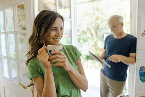 Mature couple at home with woman drinking coffee and man reading newspaper - KNSF04619