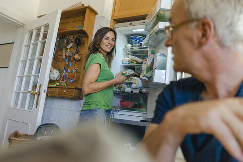 Mature couple at home with woman standing at refrigerator - KNSF04620