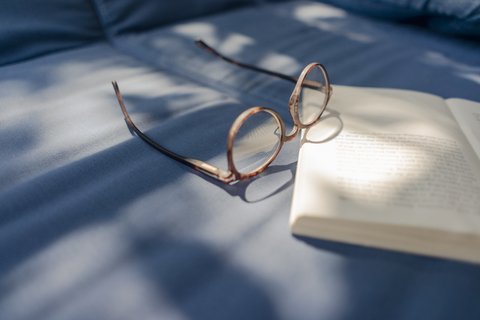 Eyeglasses and book lying on couch stock photo