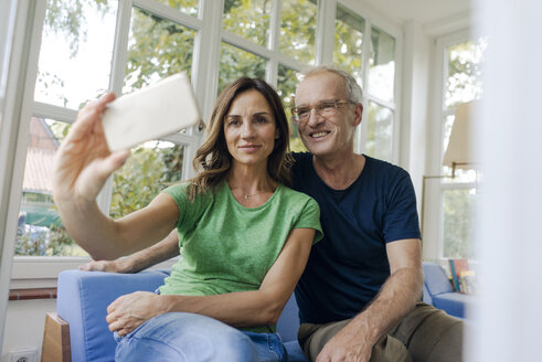 Smiling mature couple taking a selfie at home - KNSF04651