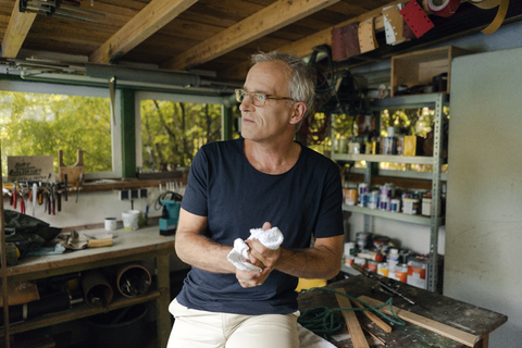 Mature man in his workshop cleaning his hands stock photo
