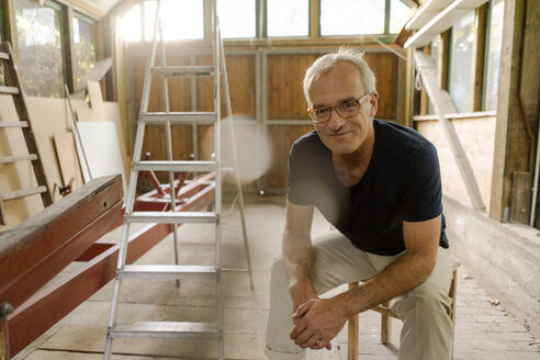 Porträt eines selbstbewussten reifen Mannes, der in seiner Werkstatt sitzt - KNSF04680