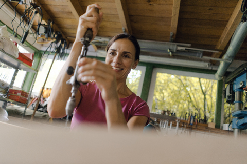 Lächelnde reife Frau bei der Arbeit in ihrer Werkstatt, lizenzfreies Stockfoto