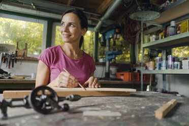 Lächelnde reife Frau an der Werkbank in ihrer Werkstatt - KNSF04683