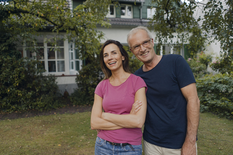 Ein glückliches reifes Paar steht im Garten seines Hauses, lizenzfreies Stockfoto