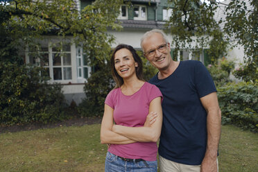 Happy mature couple standing in garden of their home - KNSF04702