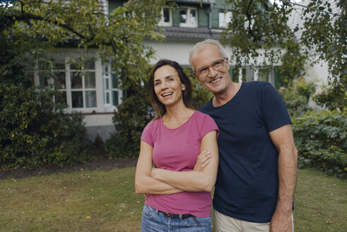 Ein glückliches reifes Paar steht im Garten seines Hauses - KNSF04702