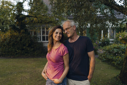 Smiling mature couple standing in garden of their home - KNSF04705