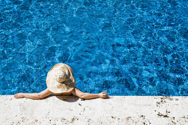 JAMAIKA: Eine Frau mit einem riesigen Strohhut entspannt sich am Rande eines blauen Pools. - AURF02476