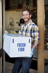 Man carrying box in fish store - AURF02498