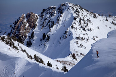 Ein Skitourengeher steht am Rande einer Klippe und blickt auf große Berge. - AURF02516