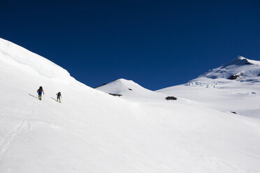 Skifahrer fahren bei Sonnenaufgang an einem Blue-Bird-Tag eine weite offene Schüssel hinauf. - AURF02554
