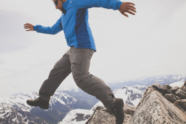 Ein Wanderer springt zwischen zwei Felsen auf dem Gipfel des Needle Peak, BC, Kanada. - AURF02638