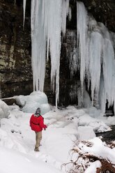 Ein Mann blickt auf große Eiszapfen, während er versucht, mit der Fliege zu angeln. - AURF02683