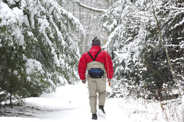 Ein Mann geht an einem kalten, verschneiten Wintertag durch den Wald, um Fliegenfischen zu gehen. - AURF02687