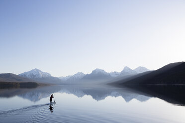 Ein Mann steht auf einem Stand Up Paddle Board (SUP) auf dem ruhigen Lake McDonald im Glacier National Park. - AURF02704