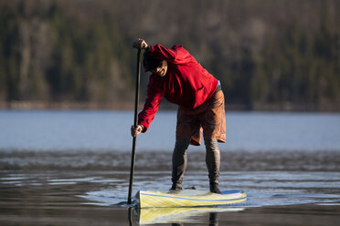 Ein Mann steht auf einem Stand Up Paddle Board (SUP) auf dem ruhigen Lake McDonald im Glacier National Park. - AURF02707