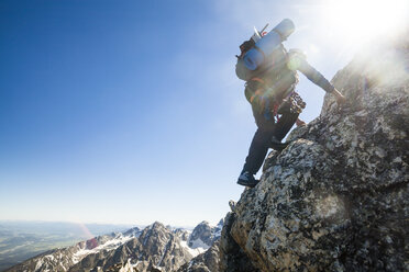 Ein Mann klettert auf dem Teewinot Mountain, Grand Teton National Park, Wyoming, in die Sonne. - AURF02740