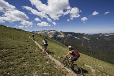 Drei Mountainbiker fahren auf einem Weg durch die Berge. - AURF02776