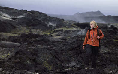 Frau beim Wandern durch ein Lavafeld am Vulkan Krafla / Nordisland - AURF02824