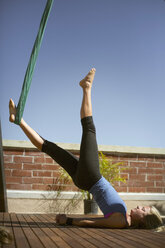 Ein wunderschönes Mädchen führt Aerial Yoga durch. - AURF02893