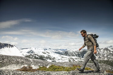 Ein Rucksacktourist wandert über Granitfelsen in einem subalpinen Gelände. - AURF02916
