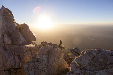 Ein Bergsteiger beobachtet den Sonnenaufgang von unterhalb des Gipfels des Teewinot Mountain im Grand Teton National Park, Wyoming. - AURF02932