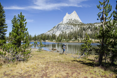 A young man walks past Cathedral Lake during a 27.3 mile backpacking trip from Tuolumne Meadows to Yosemite Valley, California. - AURF02988