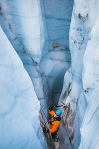 Eine Eiskletterin schwingt ihre Eisgeräte in einer Gletschermühle auf dem Root Glacier im Wrangell-St. Elias National Park, Alaska. - AURF03003