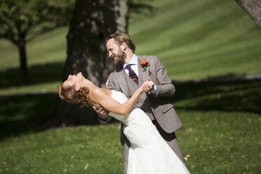 Bearded groom in grey suit dipping a laughing bride - AURF03006