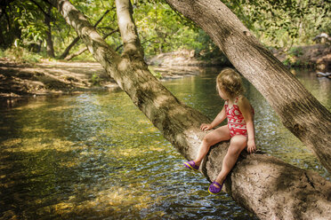 Before swimming, toddler girl rests on tree that branches over creek in Bidwell Park, Chico, California. - AURF03013