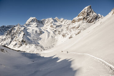 Skitourengeher beim Aufstieg auf einen Gipfel oberhalb von Devero, mit dem Monte Cervandone und der Rossa-Spitze im Hintergrund. Devero, Ossola, Italien. - AURF03049