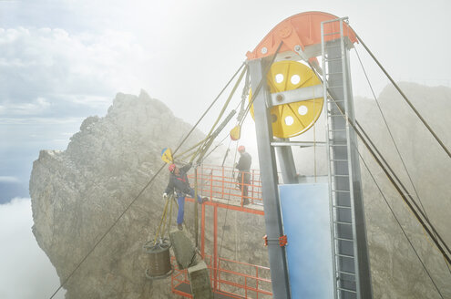 Deutschland, Bayern, Garmisch-Partenkirchen, Zugspitze, Monteure bei Arbeiten an einer Güterseilbahn - CVF01070