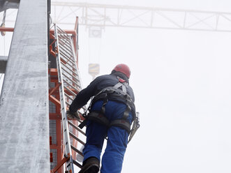 Germany, Bavaria, Garmisch-Partenkirchen, Zugspitze, installer climbing ladder on pole at goods cable lift - CVF01072