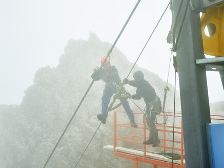 Deutschland, Bayern, Garmisch-Partenkirchen, Zugspitze, Monteure arbeiten am Stahlseil einer Güterseilbahn - CVF01080